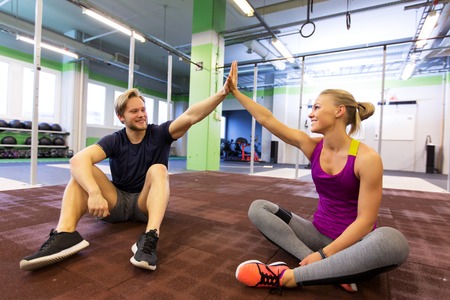 happy couple making high five in gymの写真素材