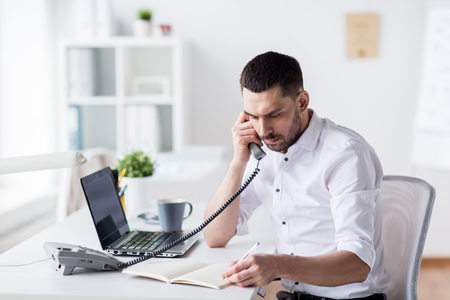 businessman with pad calling on phone at officeの写真素材