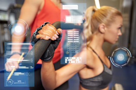 man and woman flexing muscles on gym machineの写真素材
