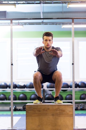 fitness, sport, training, exercising and people concept -young man doing box jumps exercise in gymの写真素材