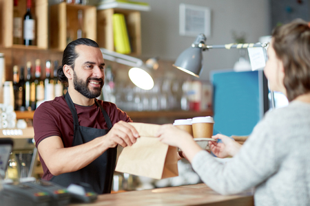 man or waiter serving customer at coffee shopの写真素材