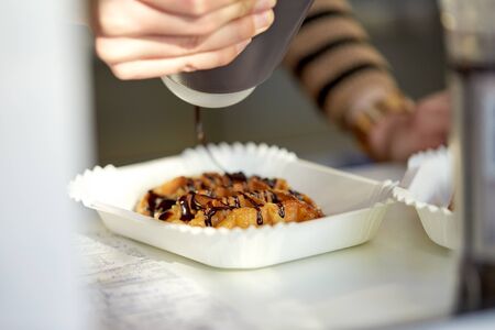food, cooking, dessert and people concept - close up of cook adding chocolate syrup to waffleの写真素材
