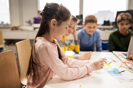 education, children, technology, science and people concept - group of happy kids with invention kit at robotics school lessonの写真素材
