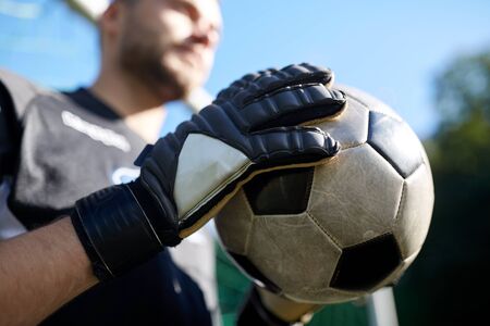 sport and people - close up of soccer player or goalkeeper holding ball at football goal on field