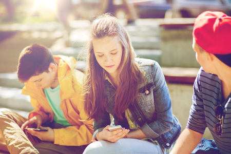teenage friends with smartphones outdoorsの写真素材