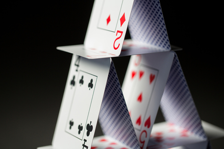 close up of house of playing cards over black