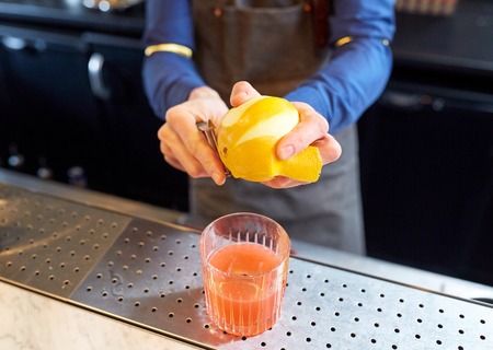 bartender removing peel from lime at barの写真素材