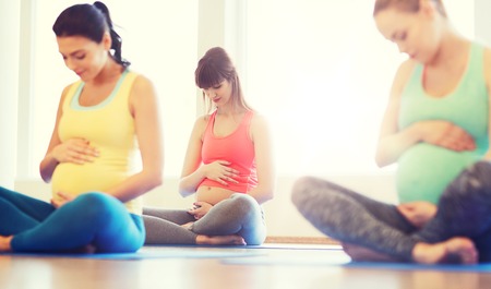 happy pregnant women exercising yoga in gymの写真素材