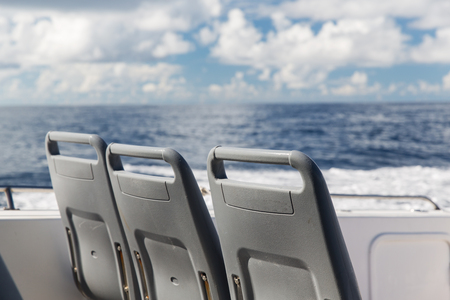 vacation, travel, cruise and tourism concept - seats on deck of passenger ship sailing in seaの写真素材