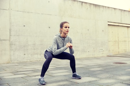 happy woman doing squats and exercising outdoorsの写真素材