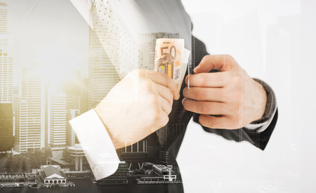 business, finances and people concept - close up of businessman with euro money over city with double exposureの写真素材