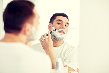 man shaving beard with razor blade at bathroomの写真素材