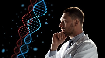 genetics, science and people concept - male doctor or scientist in white coat looking at virtual projection of dna molecule over black backgroundの写真素材