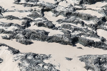 background and texture concept - close up of stone or volcanic rock surface with sandの写真素材