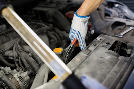 car service, repair, maintenance and people concept - auto mechanic man with lamp and pliers working at workshopの写真素材