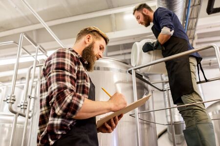 manufacture, business and people concept - men working at craft brewery or beer plantの写真素材