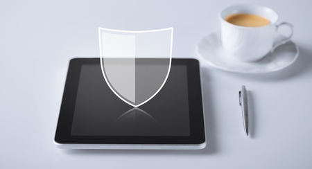 internet security, technology and cyber protection concept - virtual antivirus program shield icon over tablet pc computer with cup of coffee and penの写真素材