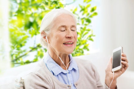 technology, age and people concept - happy senior woman with smartphone and earphones listening to...