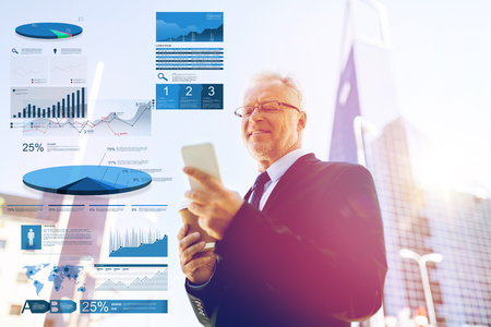 business, statistics and people concept - senior businessman with coffee cup and smartphone in city with chartsの写真素材
