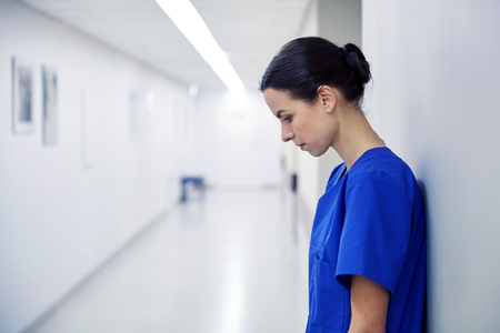 sad female nurse at hospital corridorの写真素材
