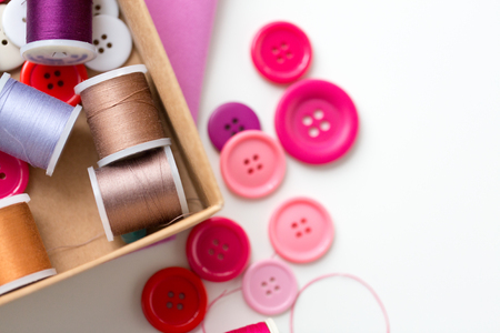 box with thread spools and sewing buttons on tableの写真素材