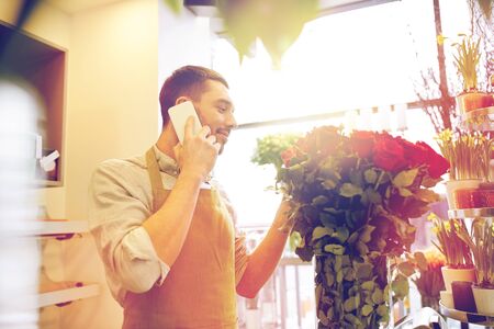 man with smartphone and red roses at flower shopの写真素材