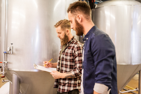 men with clipboard at craft brewery or beer plantの写真素材