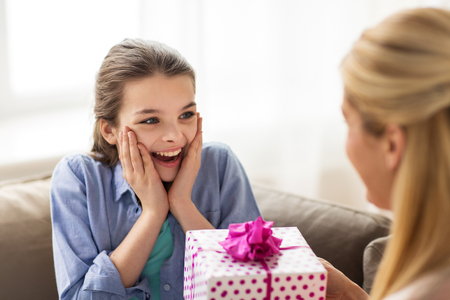 mother giving birthday present to girl at homeの写真素材