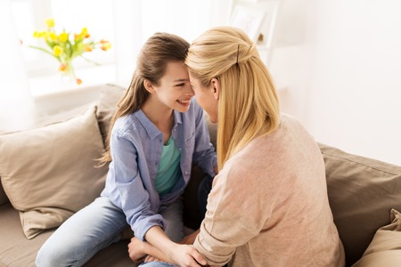 happy smiling family of girl and mother at homeの写真素材