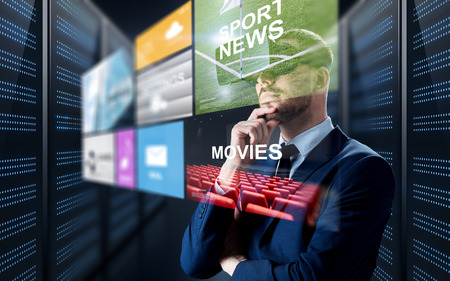 business, people and technology concept - businessman in virtual reality headset with multi media projection over futuristic server room backgroundの写真素材