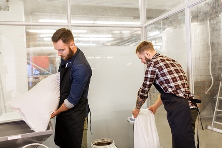 manufacture, business and people concept - men with bags weighing and pouring malt to mill at craft brewery or beer plantの写真素材