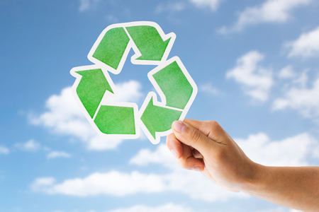 close up of hand with green recycle sign over skyの写真素材