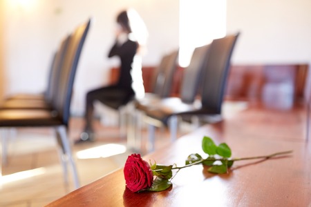 red roses and woman crying at funeral in churchの写真素材