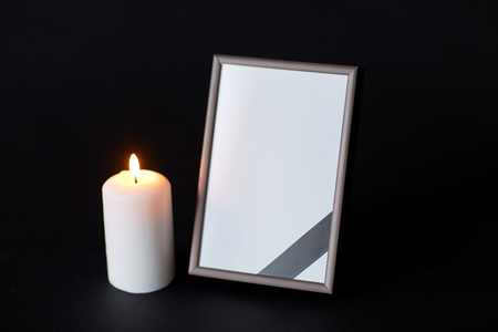 black ribbon on photo frame and candle at funeralの写真素材