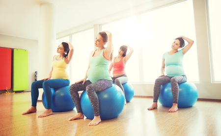 happy pregnant women exercising on fitball in gymの写真素材