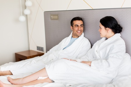 people, leisure and vacation concept - happy couple in bed at home or hotel roomの写真素材