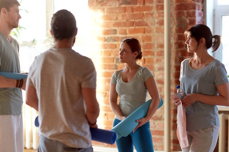 group of people with mats at yoga studio or gym