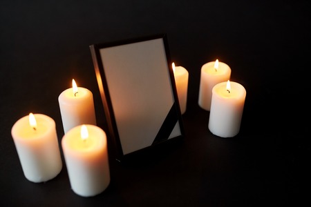 photo frame with black mourning ribbon and candlesの写真素材