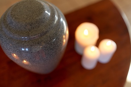 cremation urn and candles burning on tableの写真素材