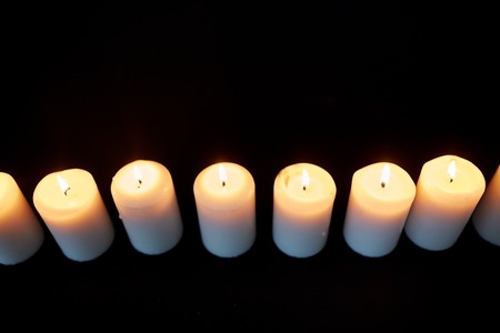 candles burning in darkness over black backgroundの写真素材