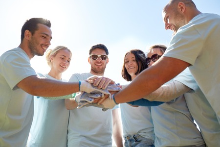 group of volunteers putting hands on top outdoors
