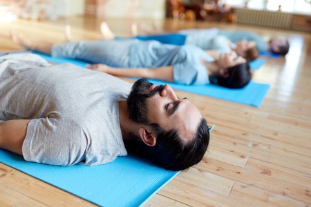 man with group of people doing yoga at studioの写真素材