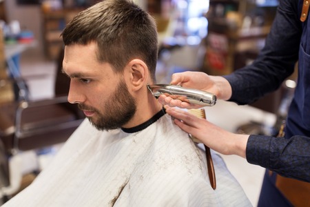 man and barber hands with trimmer cutting hairの写真素材