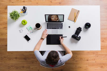 woman with camera working on laptop at tableの写真素材