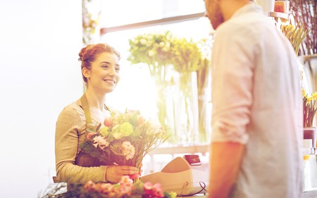 smiling florist woman and man at flower shopの写真素材