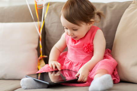 baby girl with tablet pc at homeの写真素材