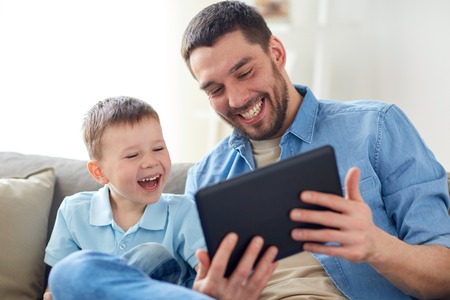 father and son with tablet pc playing at homeの写真素材