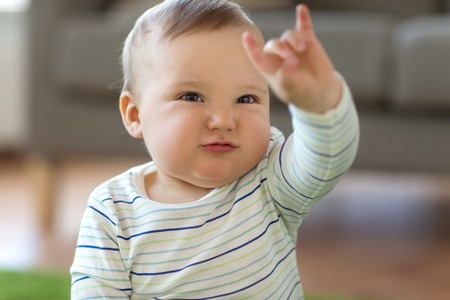 baby boy showing rock hand sign at homeの写真素材