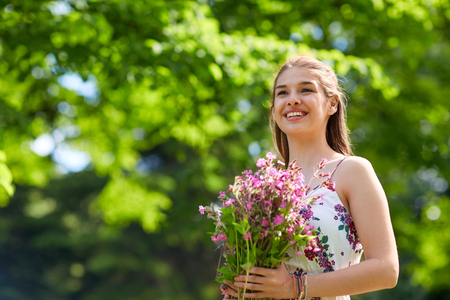 happy young woman with flowers in summer parkの写真素材