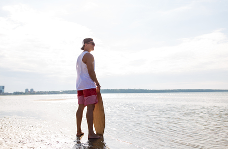 happy young man with skimboard on summer beachの写真素材